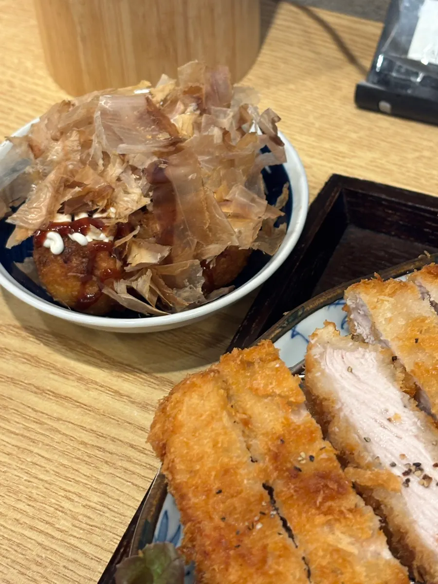 A piece of pork loin katsu dipped in sauce