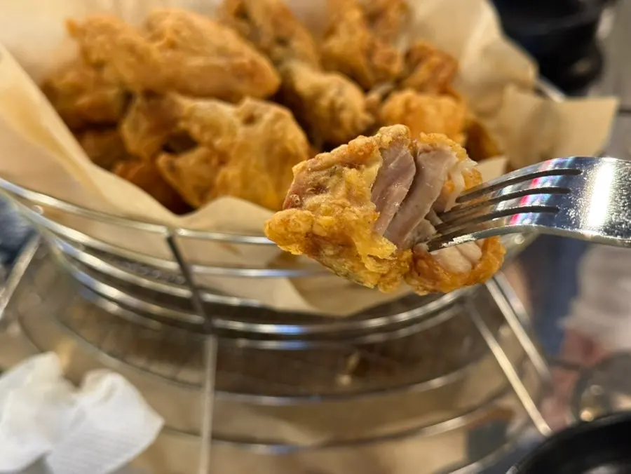 A piece of fried chicken showing juicy meat inside