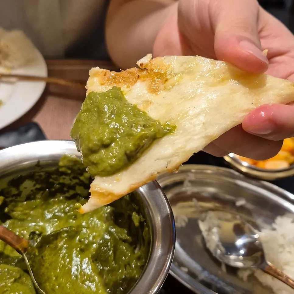 Naan topped with curry being eaten