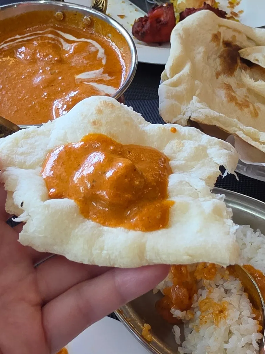 Tearing naan to dip into butter curry