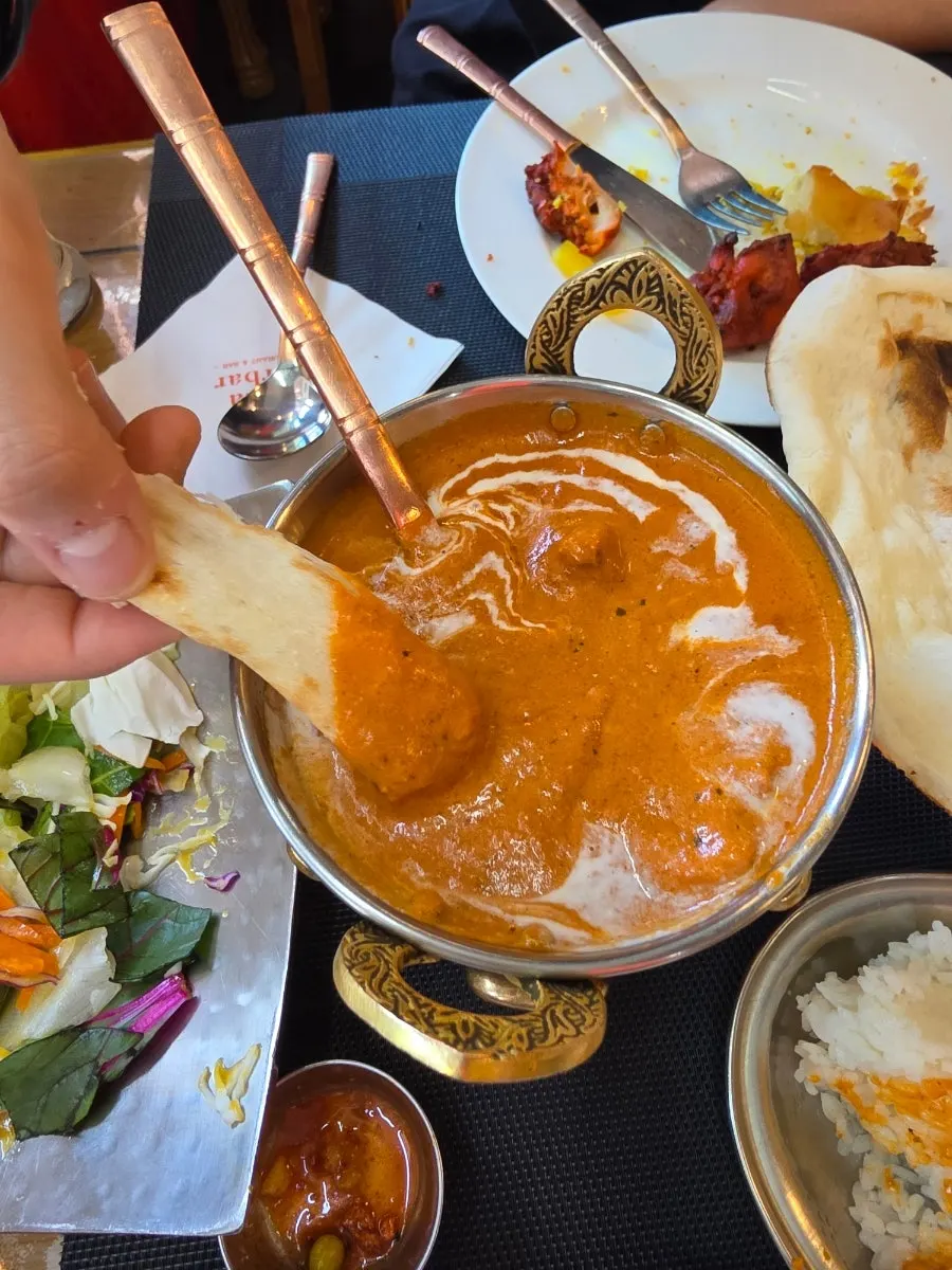 A piece of chicken placed on top of naan with butter curry