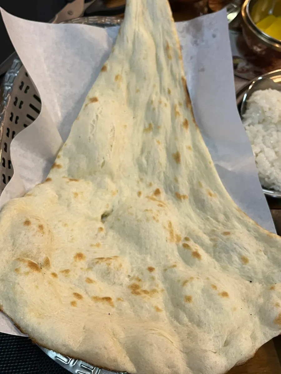 Tearing naan and dipping it into curry