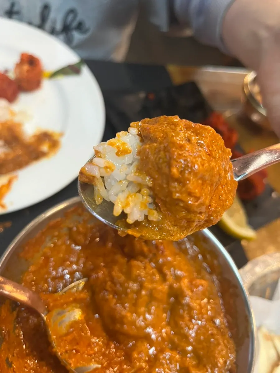 A bite combining naan and tandoori chicken