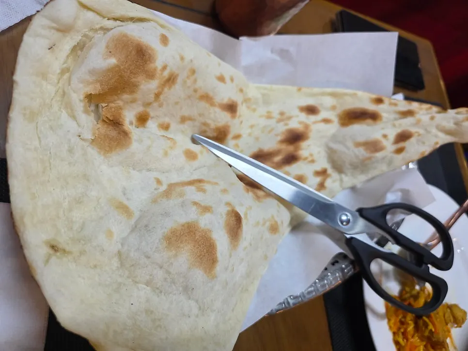A torn piece of naan dipped in curry sauce