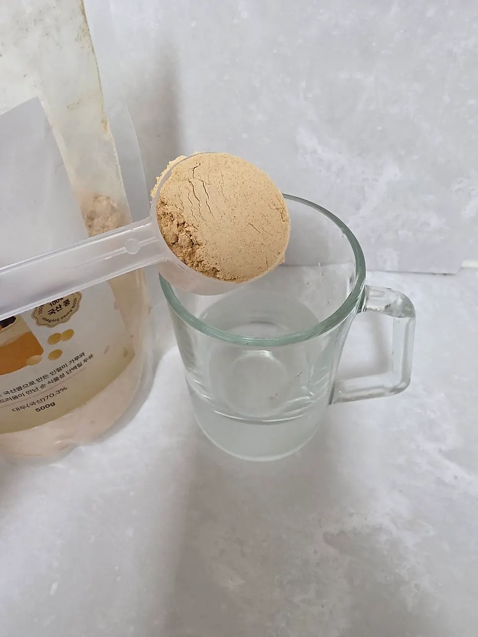 Measuring 2 scoops of soy milk powder with the dedicated scoop