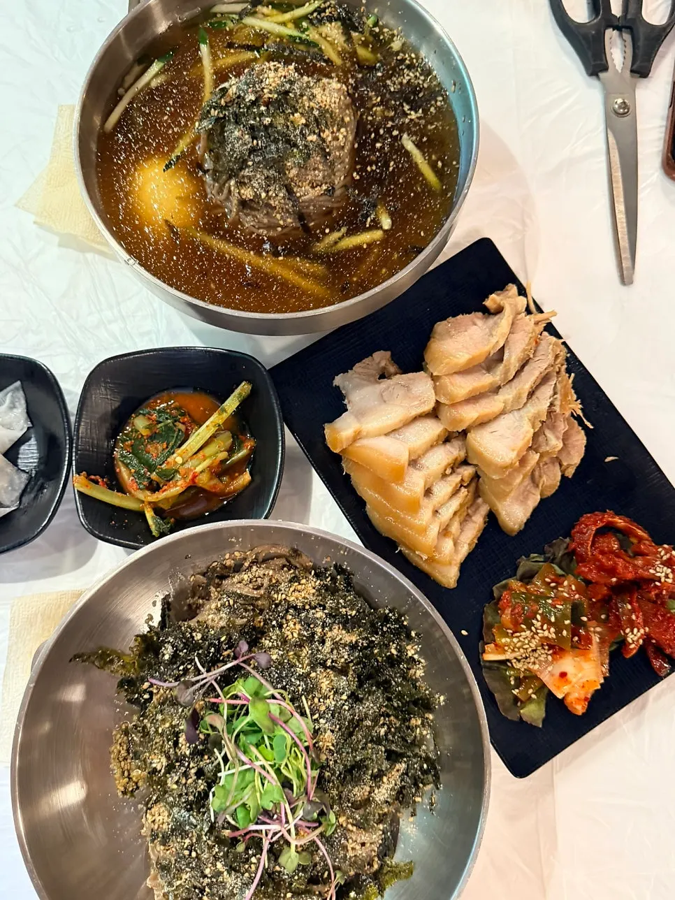 A full table with water makguksu, perilla-oil makguksu, and bossam