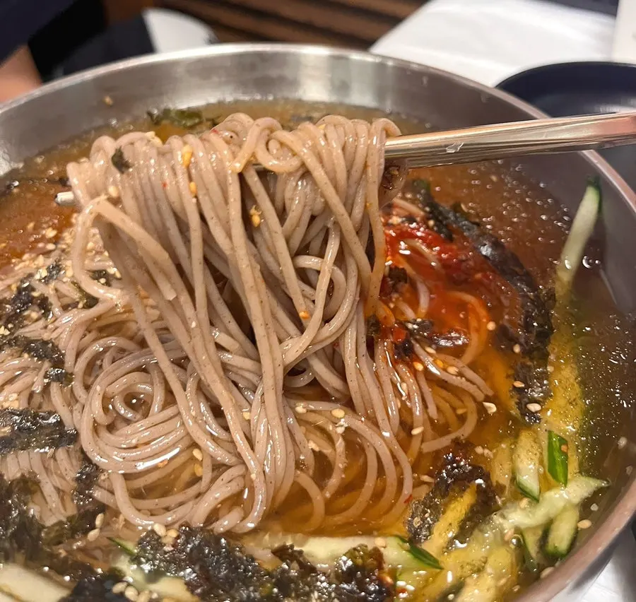 Close-up of the spicy seasoning on top of water makguksu