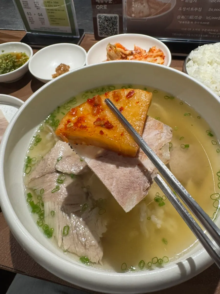 깍두기와 김치를 곁들인 곰탕 한 술
