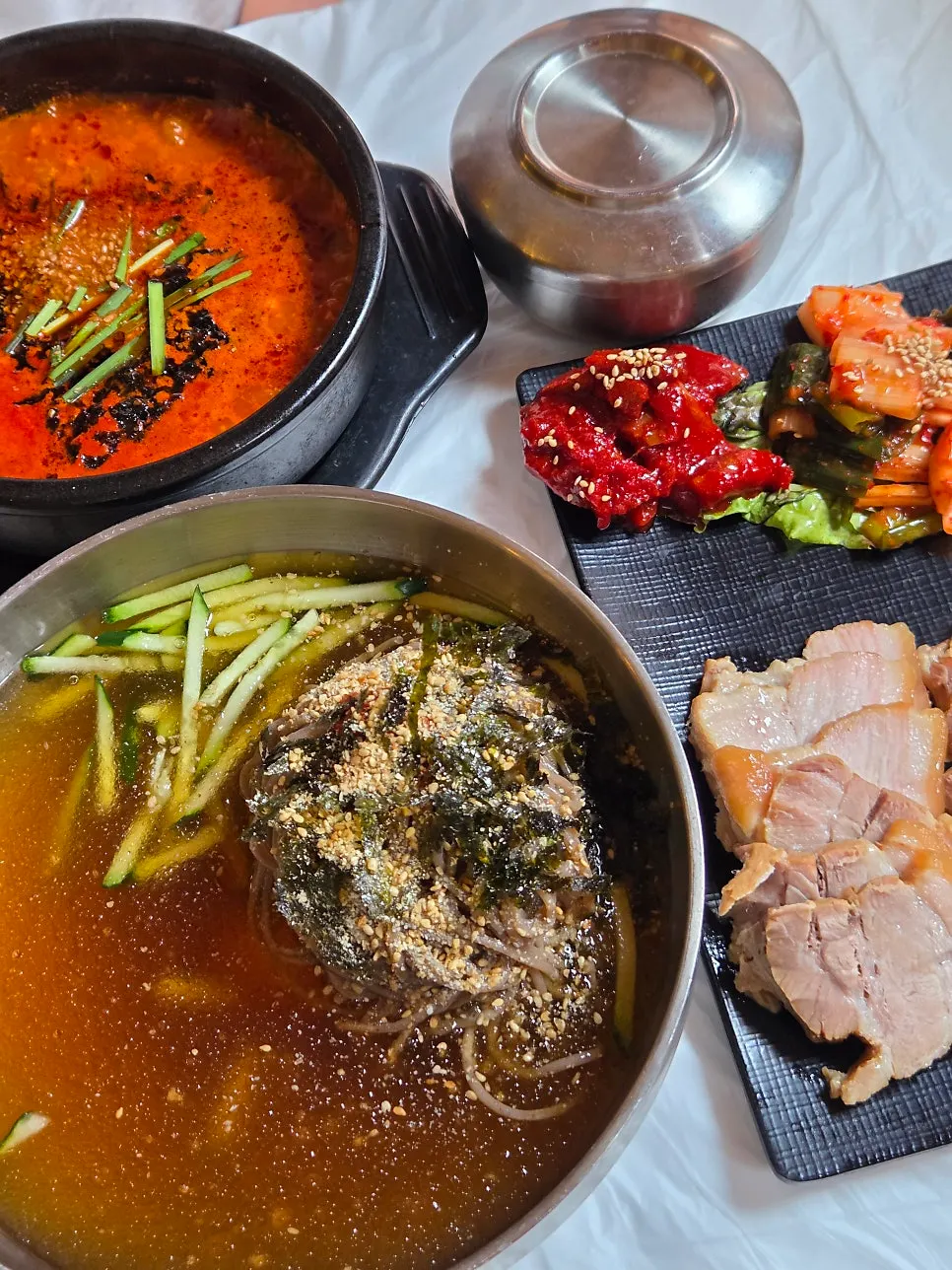 Table set for two with mul-makguksu, spicy Chodang sundubu, and bossam
