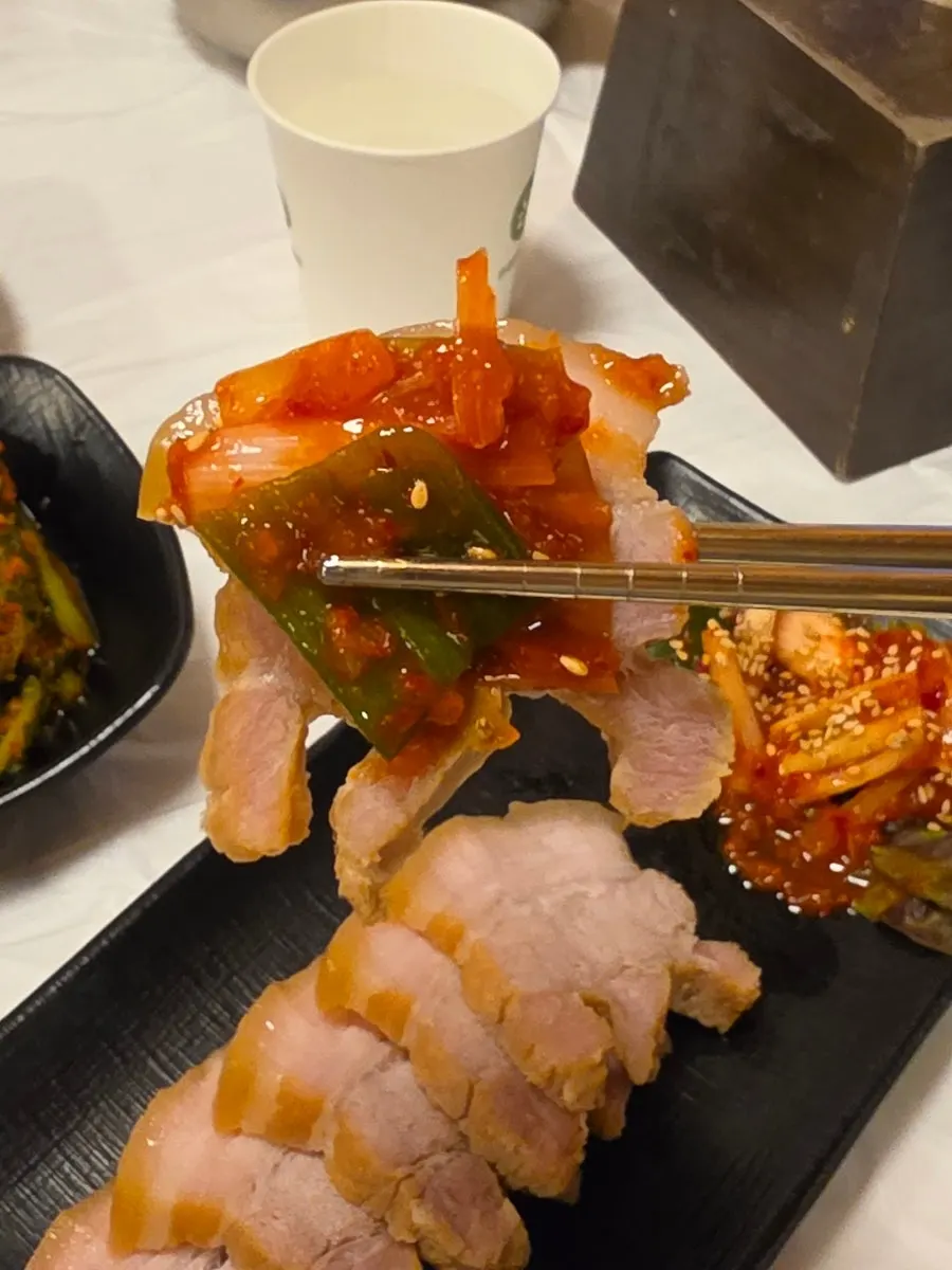 A piece of pork belly topped with green onion kimchi