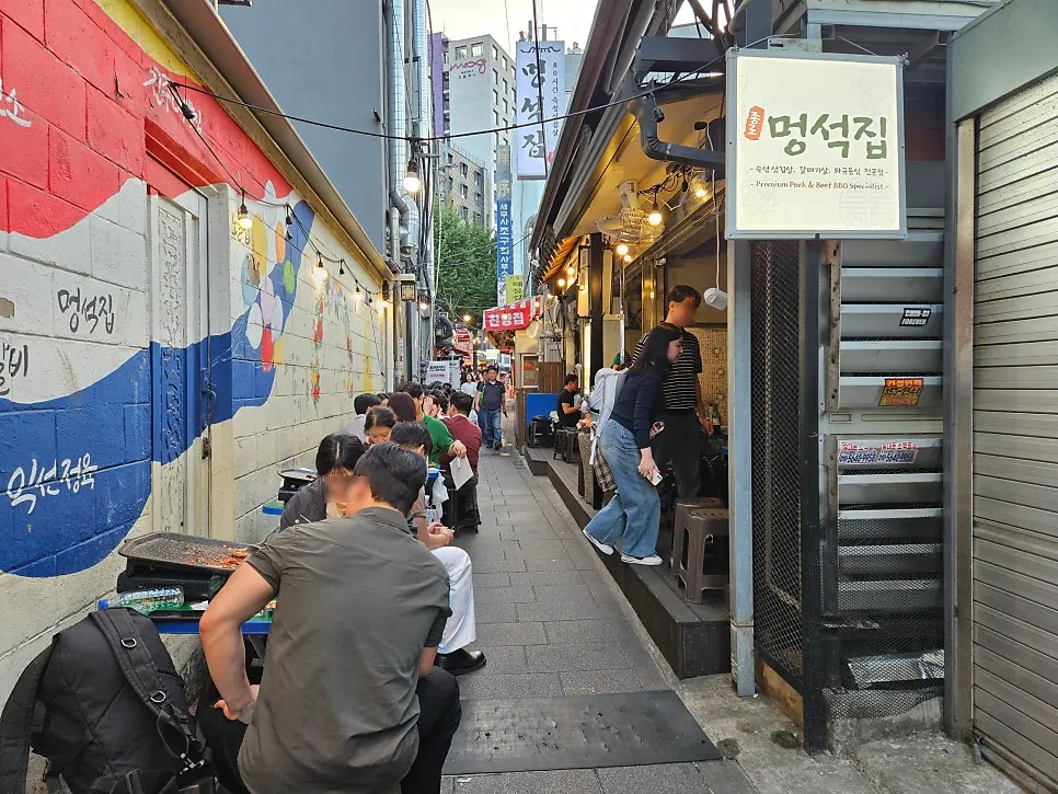 좁은 골목에 야장 테이블이 줄지어 선 멍석집 외관