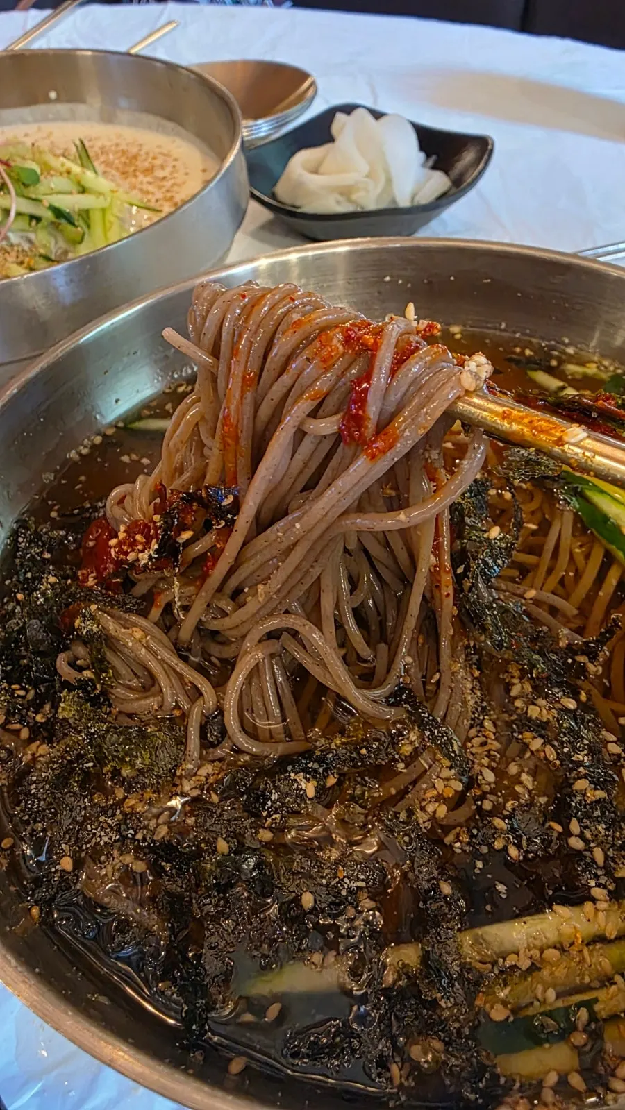 Lifting the house-made buckwheat noodles in mul-makguksu