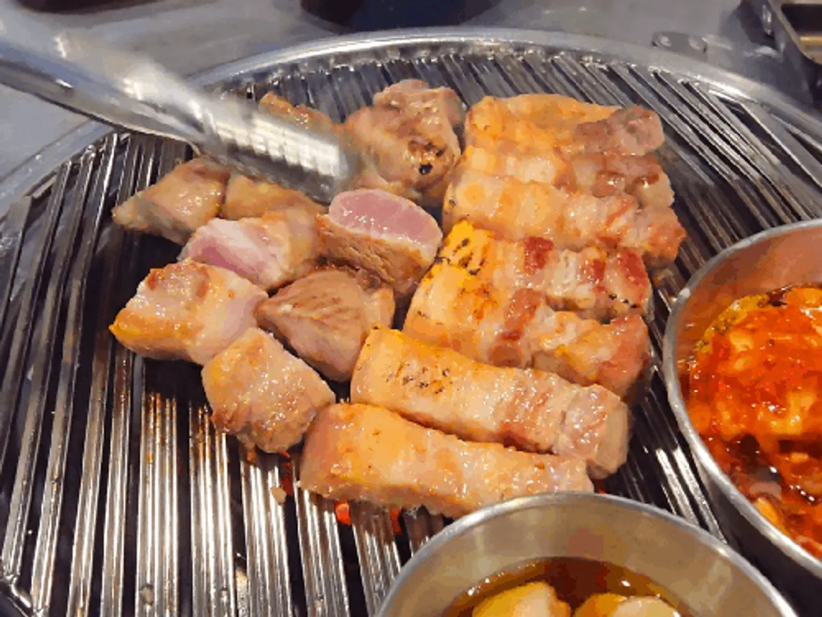Staff member slicing and grilling the ogyeopsal