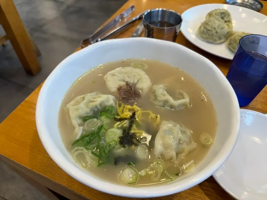 Full table spread of bibim naengmyeon, galbitang and tteok-mandu-guk