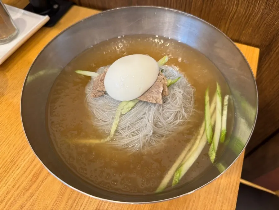 Mul naengmyeon topped with cucumber and meat garnish