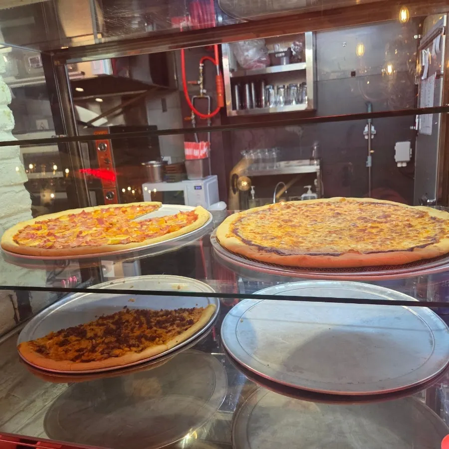 A giant pizza continuously coming out of the oven