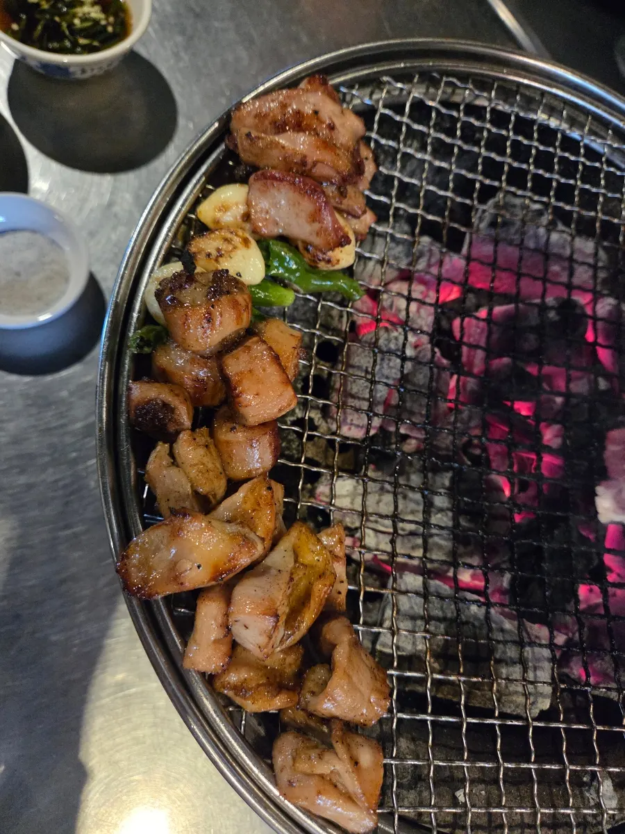 Daechang grilling over charcoal with garlic and kkwari peppers