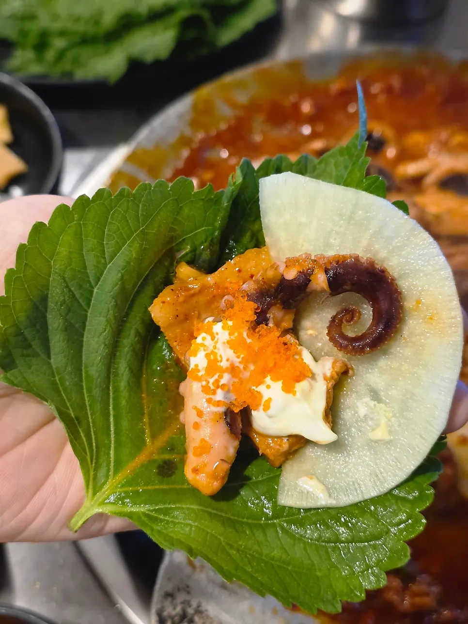 A perilla leaf wrap with octopus and pork belly