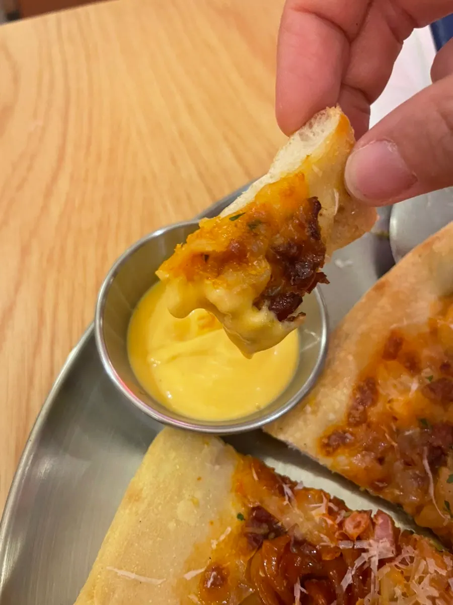 Pizza slice dipped in garlic sauce