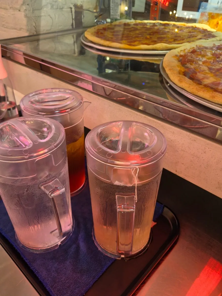 Self-serve bar with hot sauce, pepperoncino, water and tea