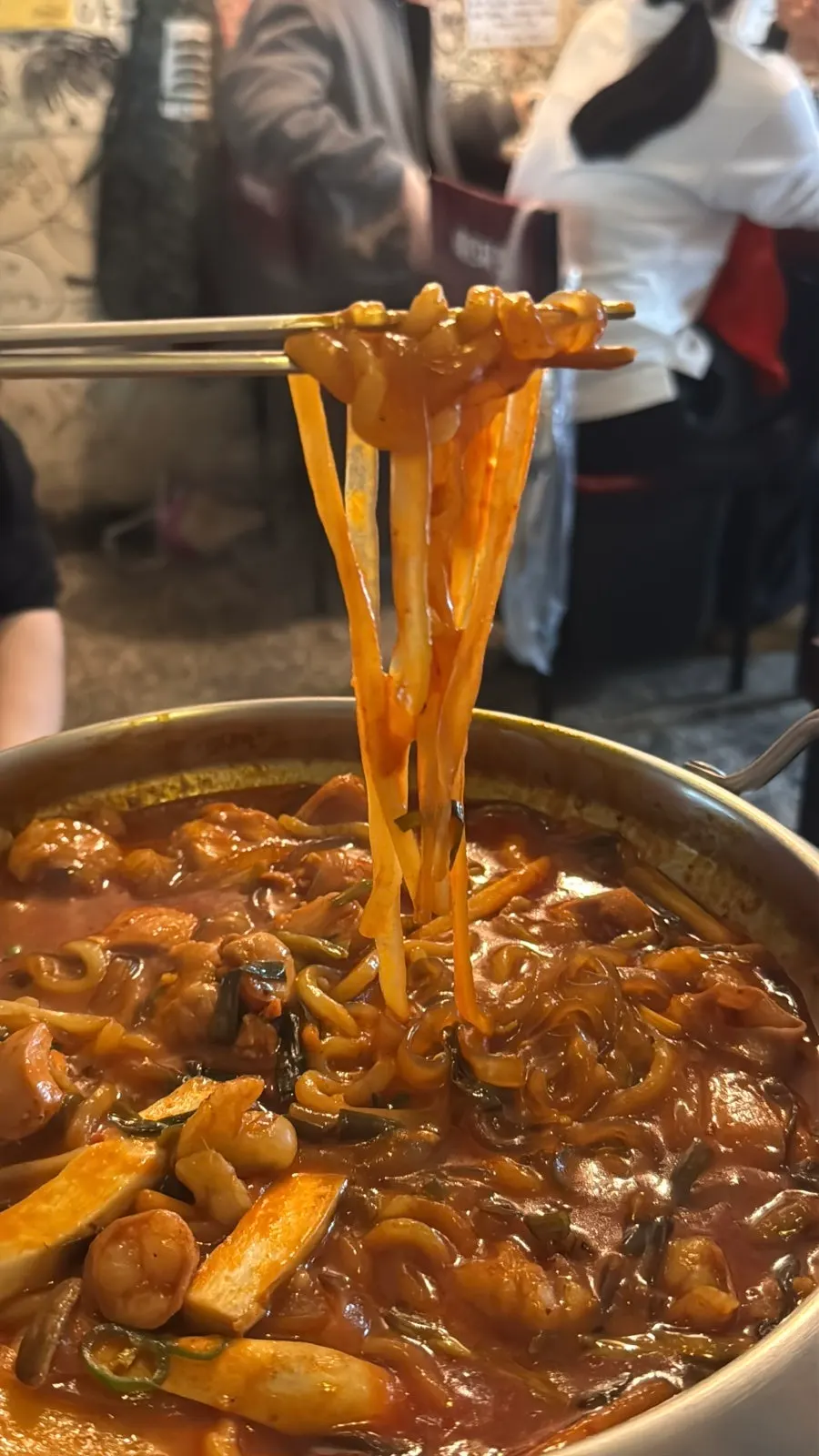 Daechang, chicken thigh, and glass noodles lifted out of the pot
