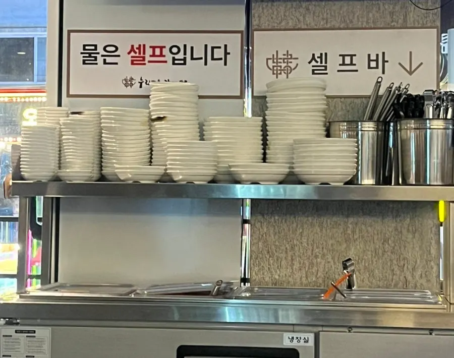 물과 밑반찬, 식기류가 놓인 셀프바