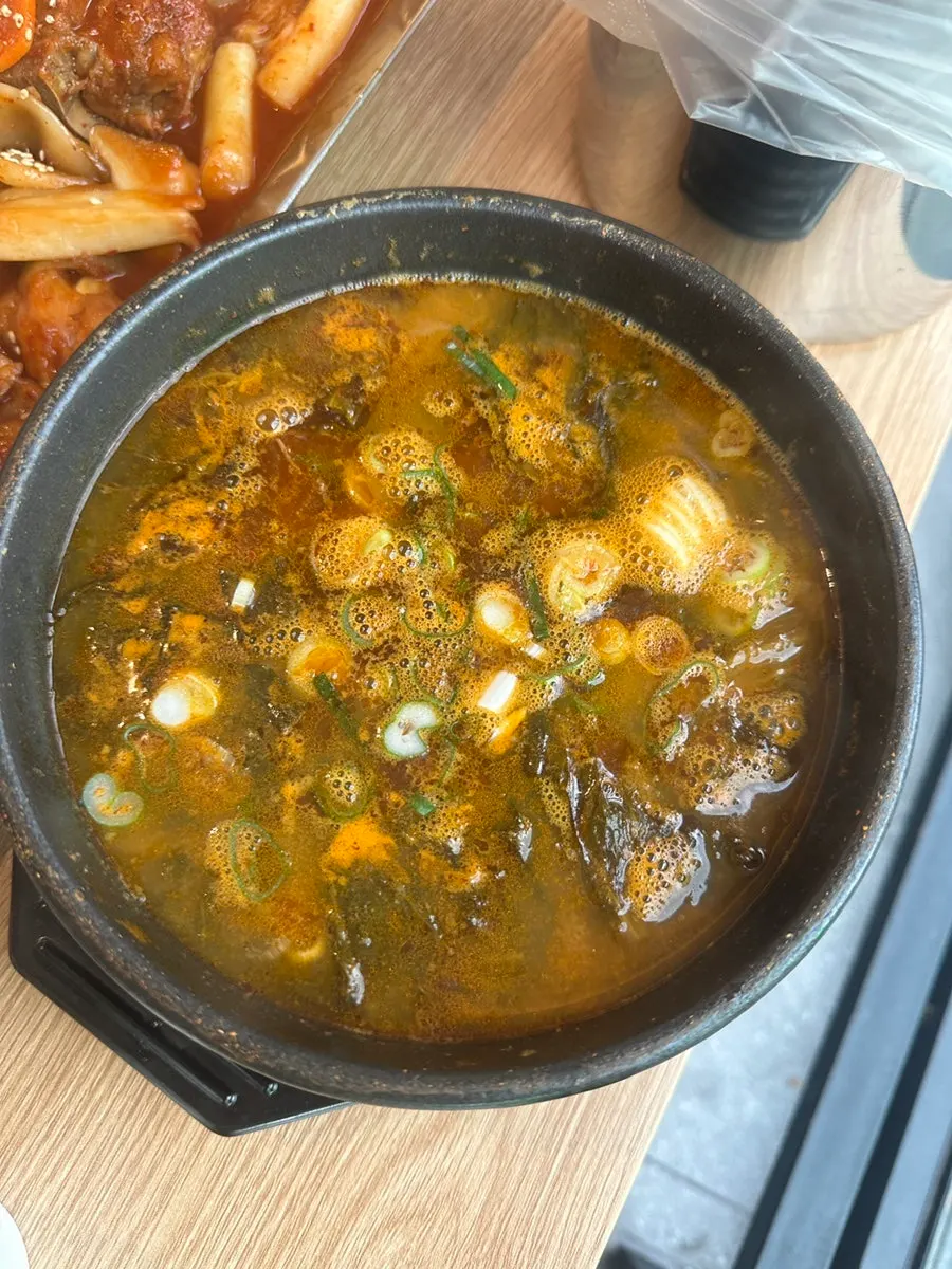 Bowl of gamjatang broth with dried radish greens, served alongside the bone stew