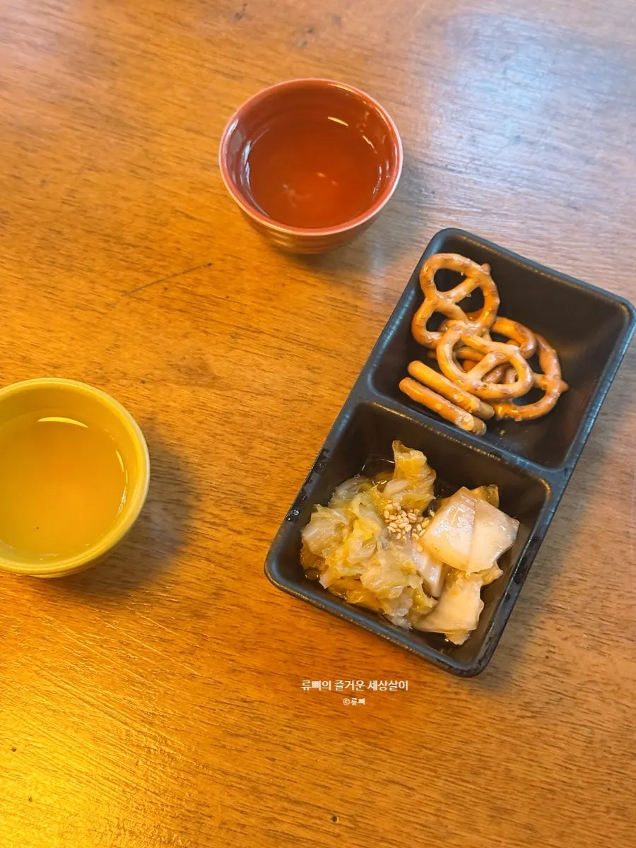 Basic side dishes of pretzels and white kimchi, with welcome drink bamboo rice wine