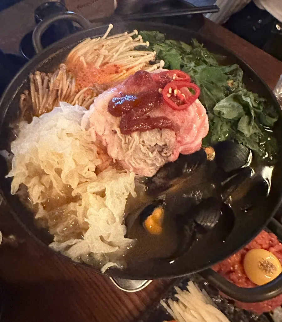 Table set with yukhoe, hotpot, and soju