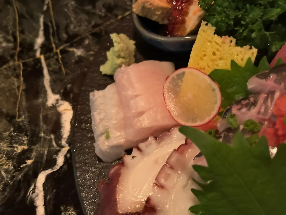 Assorted sashimi spread served alongside drinks