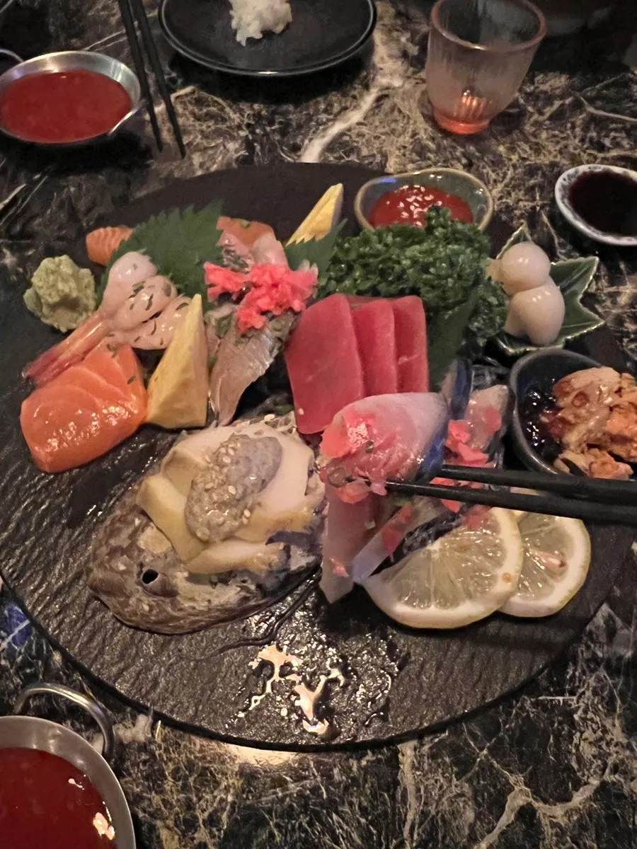 A piece of sashimi picked up with chopsticks