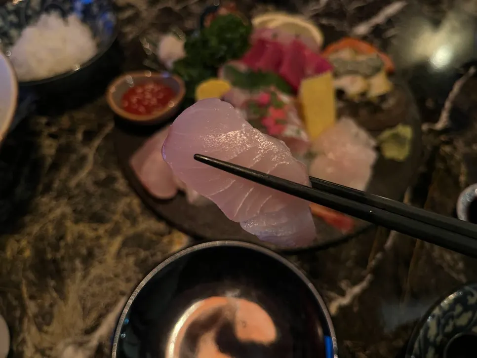 A piece of tuna sashimi dipped in wasabi soy sauce
