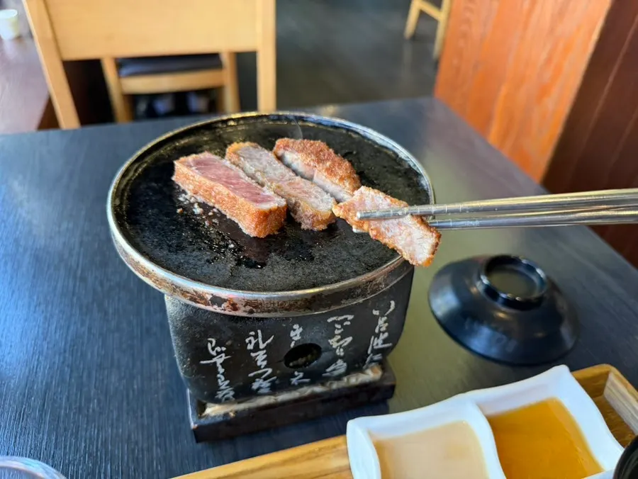Grilling a piece of gyukatsu on the mini charcoal grill