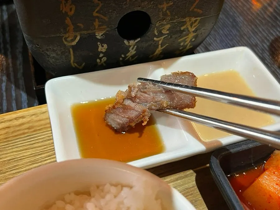 A piece of gyukatsu being dipped into the sauce