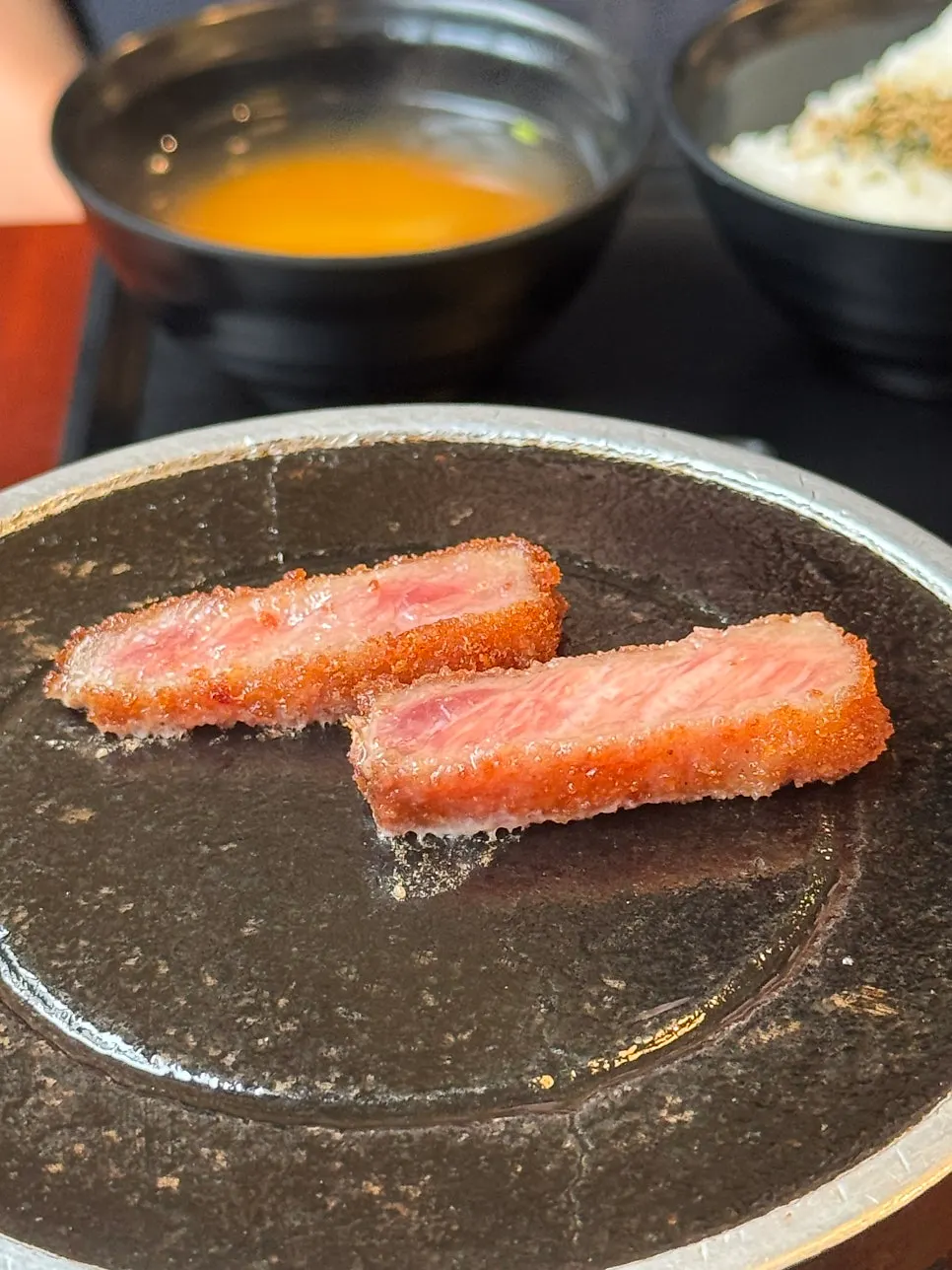 Grilling a piece of gyukatsu over the brazier