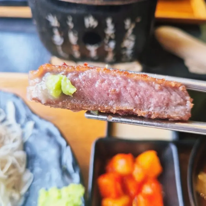 A grilled piece of gyukatsu topped with wasabi