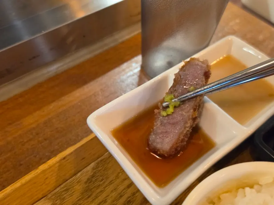 Dipping grilled gyukatsu into the special sauce