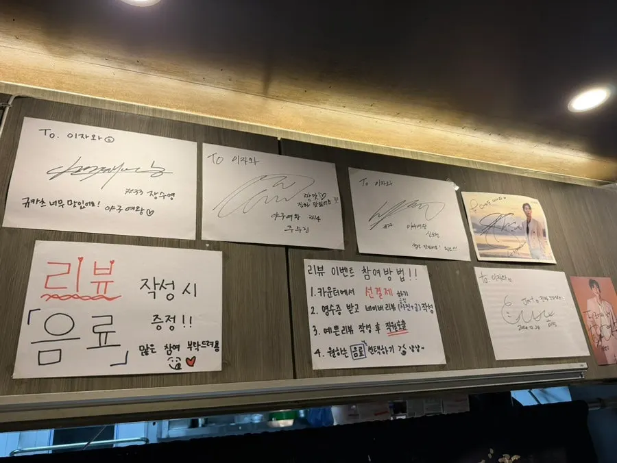 리뷰 이벤트 안내와 연예인 사인이 걸린 벽면