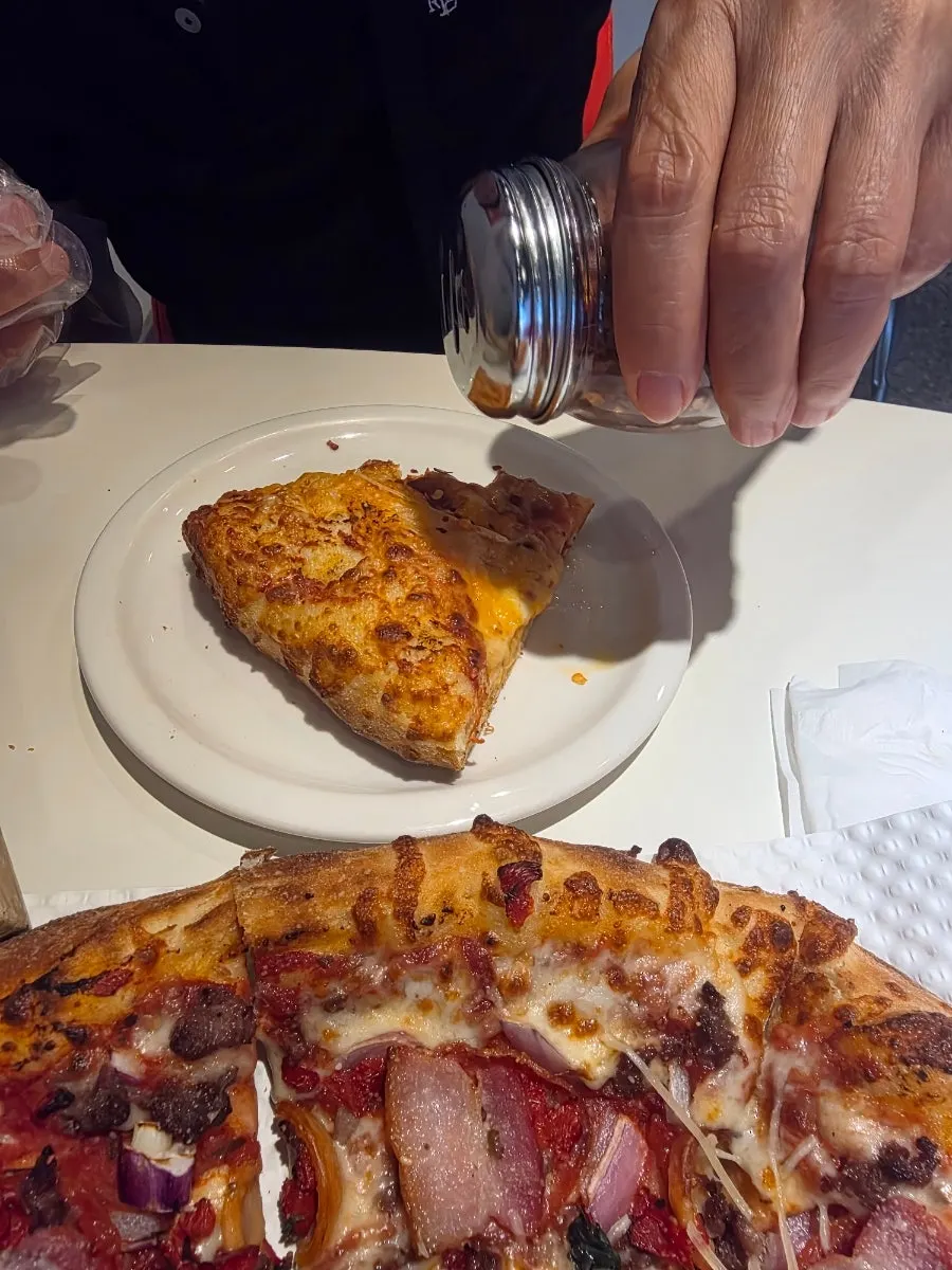 Sprinkling red pepper flakes on the pizza