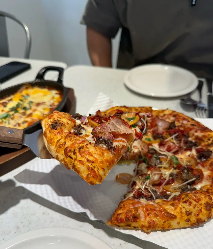 A slice topped with bacon, bulgogi, and cheese