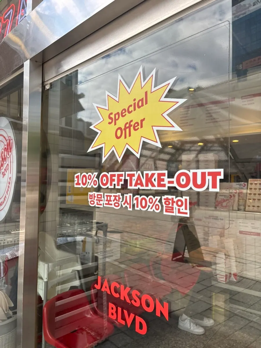 Sign explaining weekday lunch discount and other perks at Jackson Pizza Wirye Branch