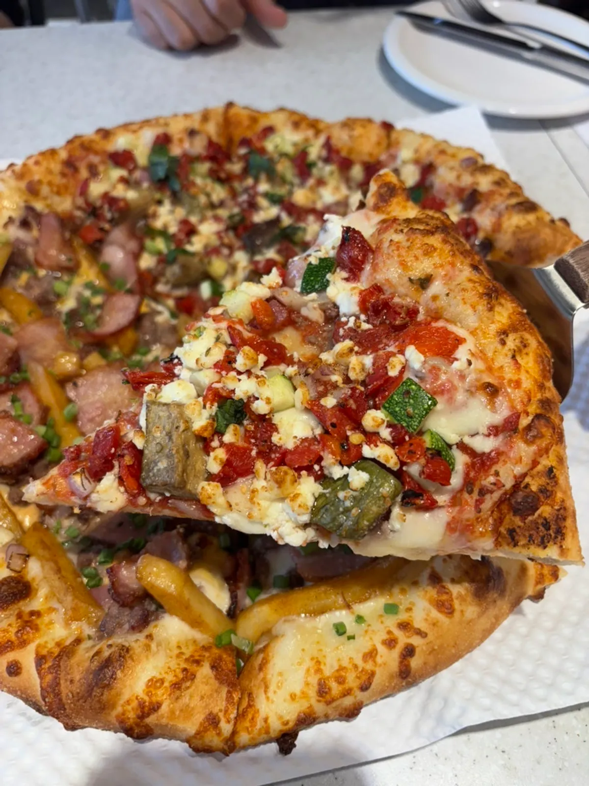 Greekology pizza topped with zucchini, eggplant, and bell peppers