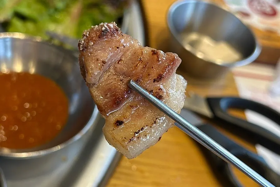 A piece of kkodeulsal dipped in salt