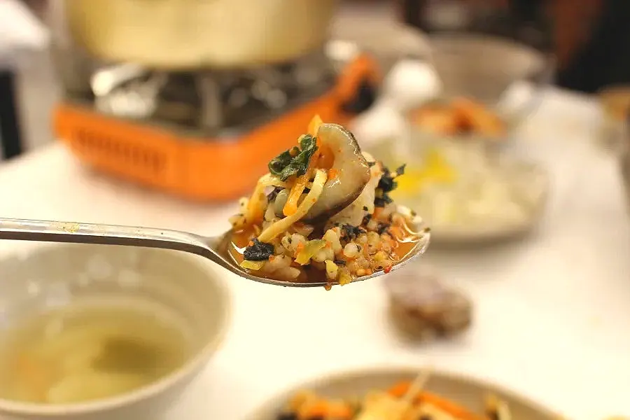 A bite of mulhoe with crunchy vegetables and seafood mixed together
