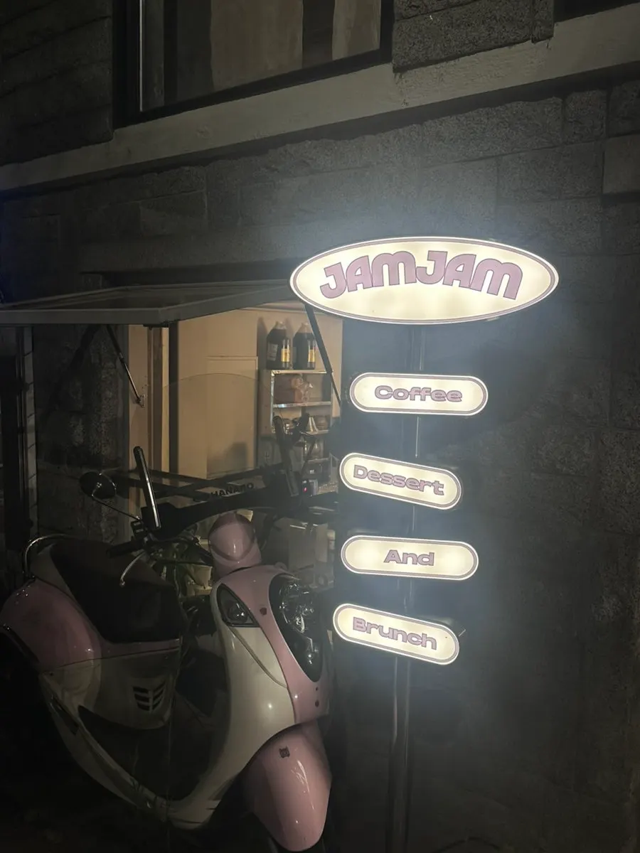 Jam Jam's exterior at night with a pink scooter