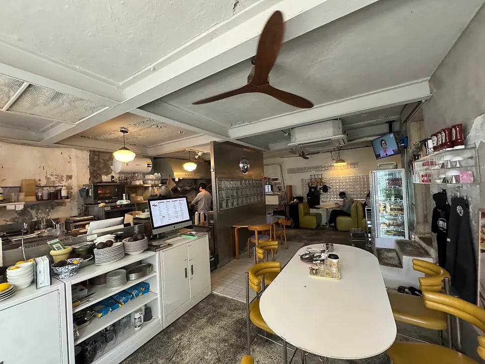 Jam Jam interior with exposed concrete walls, plants, and a round mirror