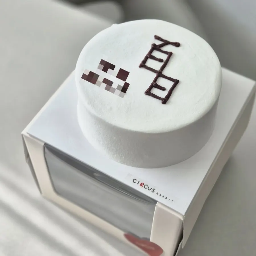 The pure white 100-day lettering cake unwrapped at home