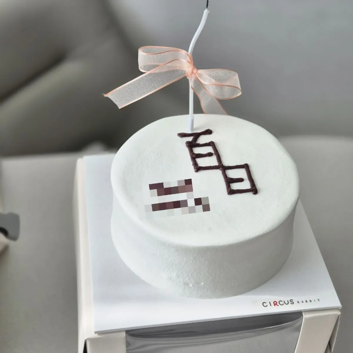 All-white whipped cream cake with lit 100-day candles