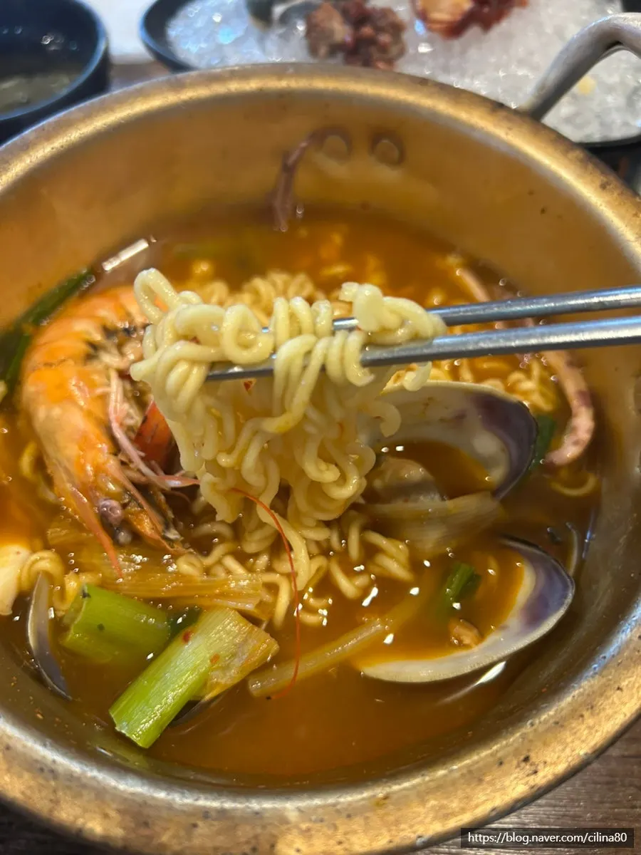 Lifting up a serving of seafood ramyeon noodles