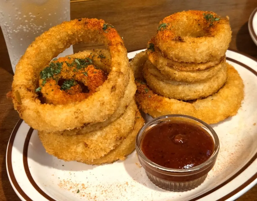 Plate of crispy onion rings sprinkled with seasoning